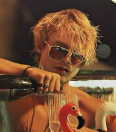 a man in sunglasses holding a wine glass and flamingo figurine next to him