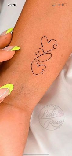 a woman's arm with yellow nail polish and a tattoo design on the wrist