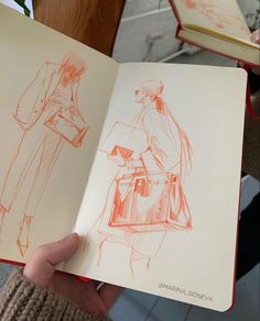 a person holding an open book with drawings on it