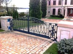 a gate that is on the side of a brick walkway in front of a house