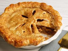 a pie sitting on top of a white plate next to a knife and fork in front of it