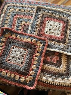 three crocheted squares sitting on top of a wooden table