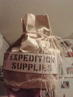 a wrapped up bag that says expedition supplies on the front and back with some string attached to it