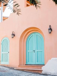 a pink building with two blue doors and green shutters