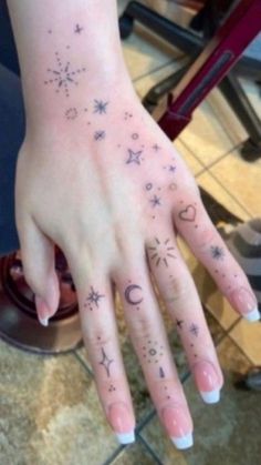 a woman's hand with stars and moon tattoos on it