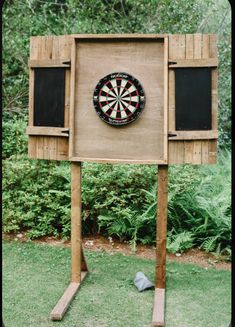 a wooden sign with a dart on it in front of some bushes and trees,