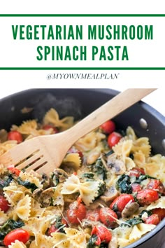 pasta with spinach and tomatoes in a skillet with a wooden spatula on the side