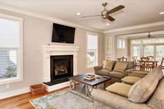 a living room filled with furniture and a flat screen tv mounted on the wall above a fire place