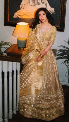 a woman in a gold sari standing next to a painting