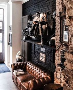 a motorcycle is mounted on a brick wall above a leather couch in the living room