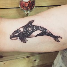 a black and white orca whale tattoo on the right arm with circles around it