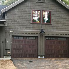 two brown garage doors are open in front of a gray house