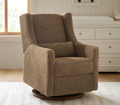 a brown recliner chair sitting on top of a wooden floor next to a window