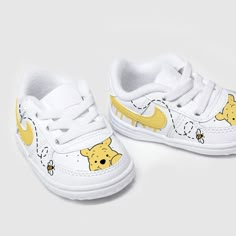 a pair of white shoes with winnie the pooh on them, both have yellow accents