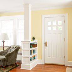 a living room with yellow walls and white trim on the doors, furniture, and bookshelves