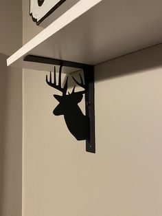 a deer head mounted to the side of a wall next to a clock on a shelf