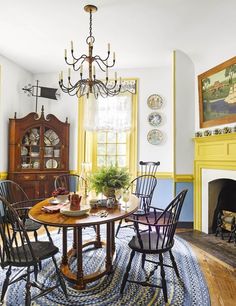 a dining room table with chairs and a chandelier in front of a fireplace