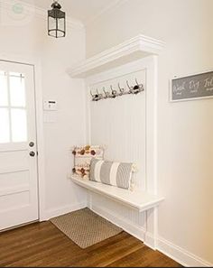 a white entryway with a bench and coat rack