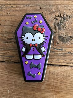 a hello kitty pin sitting on top of a wooden table