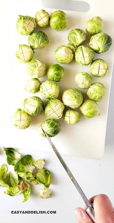 a person cutting up brussels sprouts on a cutting board with a pair of scissors