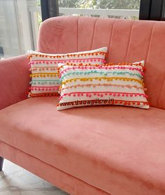 a pink couch with two pillows on it