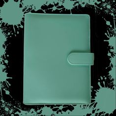 a green leather notebook with white stitching on the front and back cover, sitting on a black background