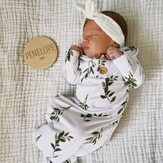 a baby laying on top of a bed next to a wooden sign