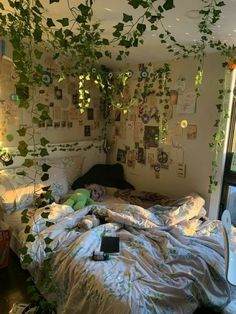 an unmade bed with lots of plants growing on the wall above it, in a bedroom