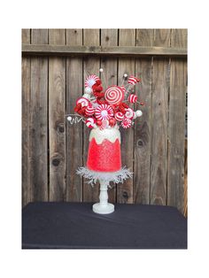 a red and white cake decorated with candy canes on a table in front of a wooden fence