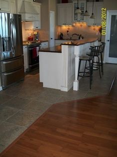 a kitchen with stainless steel appliances and wood flooring, along with white cabinetry