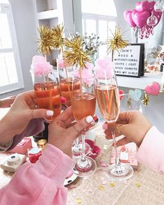 three people toasting with champagne glasses at a table filled with confetti and decorations