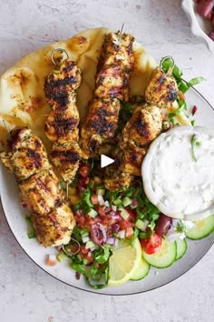 grilled chicken skewers on a plate with salad and ranch dressing