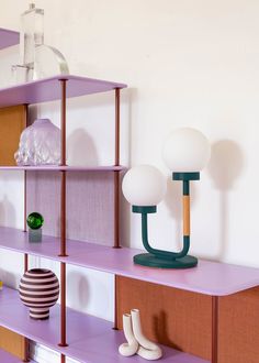 purple shelves with lamps and vases on them