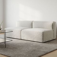 a white couch sitting on top of a wooden floor next to a table and chair