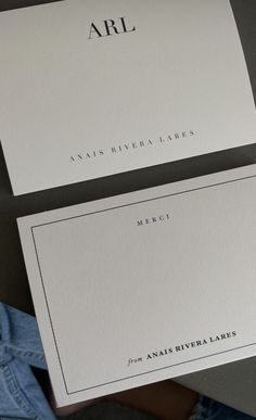 two white business cards with the word arl printed on them, sitting next to a pair of jeans