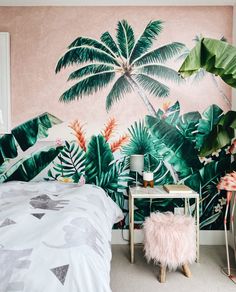 a bedroom decorated in pink and green with palm trees on the wall