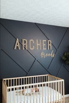 a baby's crib in front of a wall with the name archer brooks on it