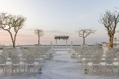 rows of white chairs are set up for an outdoor ceremony