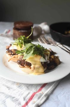 a white plate topped with food on top of a table next to a knife and fork