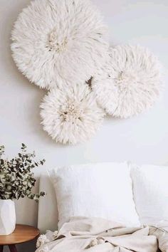 a white bed with pillows and blankets on it next to a vase filled with flowers