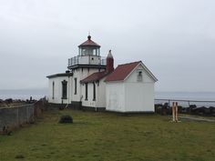 a white lighthouse sitting on top of a lush green field