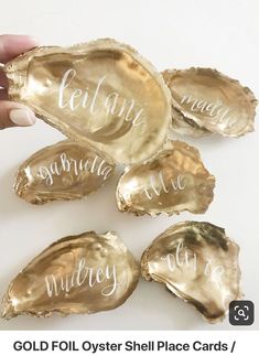 four oysters with the names of each one being held by someone's hand