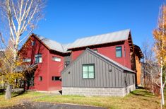 a red and gray house sitting on top of a lush green field