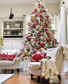 a decorated christmas tree in a living room with red and gold ornaments on the top