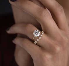 a woman's hand with a diamond ring on her finger and an engagement band