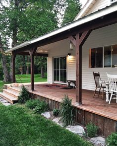 a porch with chairs and table on the side of it in front of a house