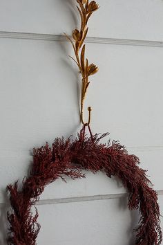 a wreath hanging from the side of a white door with gold leaves on it,