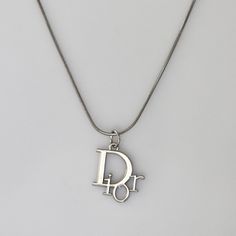 Authentic Christian Dior logo pendant set on a stainless steel 18 inch chain. Affordable Classic Silver Charm Necklaces, Luxury Silver Jewelry With Silver-tone Logo, Christian Dior Jewelry Vintage, Saint Laurent Necklace Silver, Vintage Silver Necklace With Logo Charm, Silver Charm Necklace With Logo As Gift, Mode Swag, Christian Dior Logo, Bday List