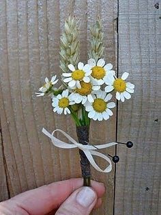 a hand holding a flower with white and yellow flowers on it, tied in a string