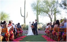 a bride and groom standing at the end of their wedding ceremony in front of cactus trees